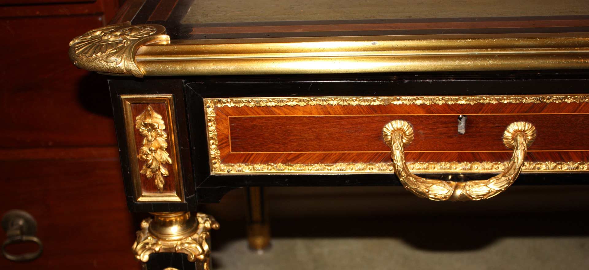 Gilt ormolu handle and mounts on a crossbanded rosewood drawer front